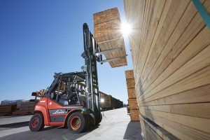 Chariot élévateur Linde soulevant des paquets de bois dans une cour à bois pour la manutention de matériaux lourds