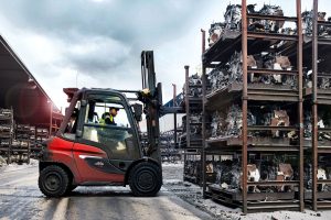 Chariot élévateur Linde transportant des pièces métalliques dans une cour industrielle de recyclage